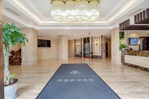A hotel lobby with a reception desk, a chandelier, and a carpet with hotel logo. - TianQuan Tianyi Jiacheng Hotel (Tianquan)