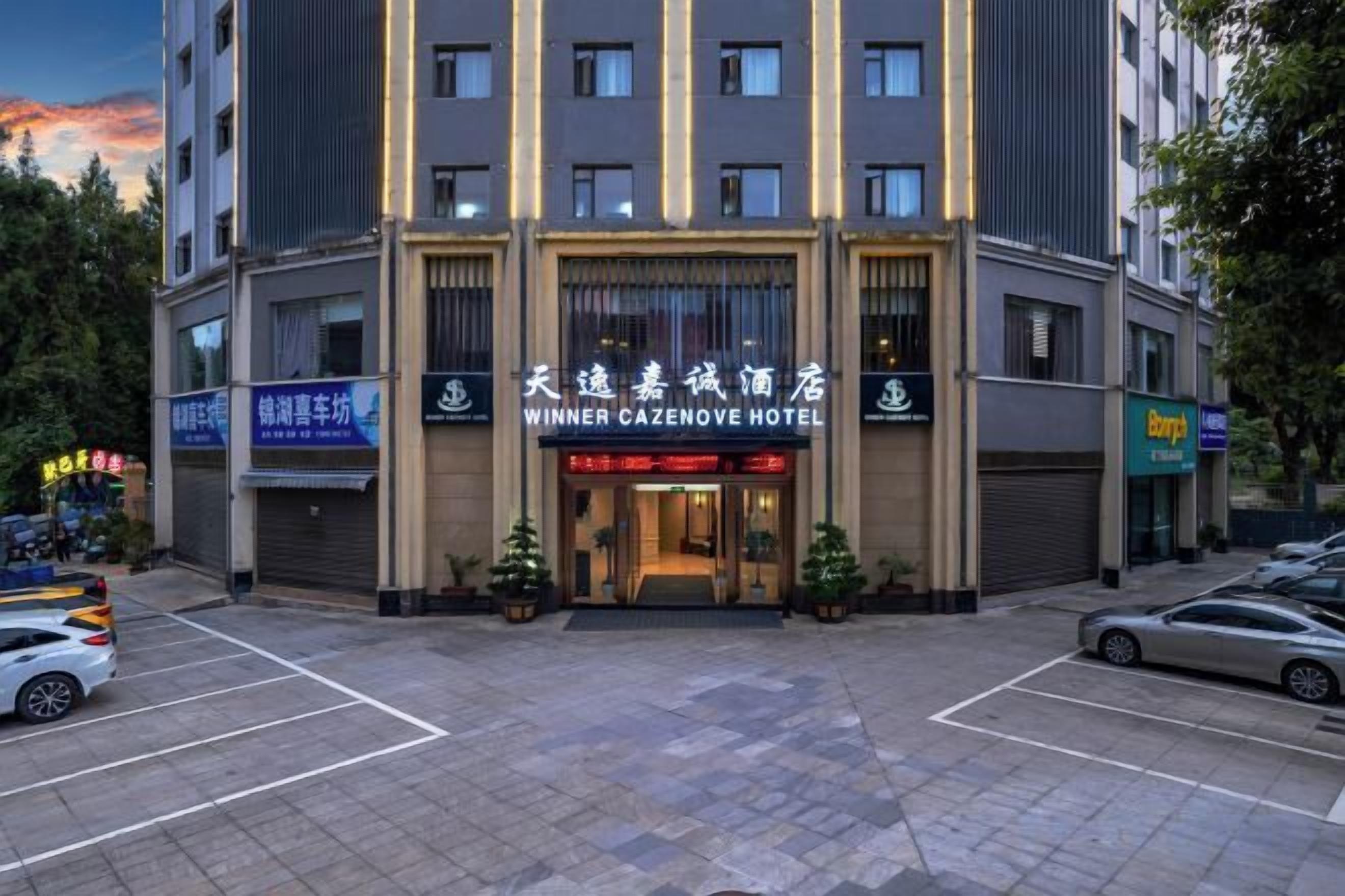 A hotel with a prominent entrance, multiple floors, and a parking lot.