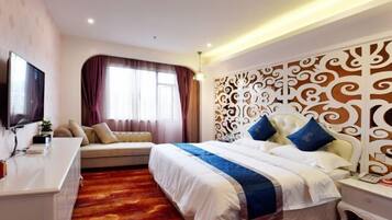 A hotel room with a large bed, a sofa, a TV, and a decorative headboard.