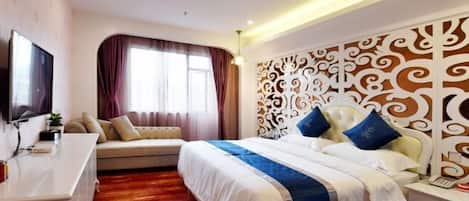 A hotel room with a large bed, a sofa, a TV, and a decorative headboard.