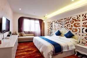 A hotel room with a large bed, a sofa, a TV, and a decorative headboard. - TianQuan Tianyi Jiacheng Hotel (Tianquan)
