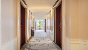 A corridor with wooden doors, a patterned carpet, and a potted plant at the end. - TianQuan Tianyi Jiacheng Hotel (Tianquan)
