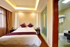 A hotel room with a large bed, a nightstand, a mirror, and a bathroom with a toilet and sink. - TianQuan Tianyi Jiacheng Hotel (Tianquan)