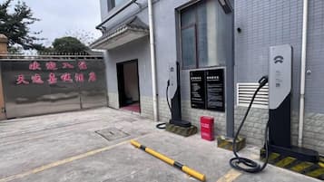 A parking area with a gated entrance, a charging station, and a signboard.