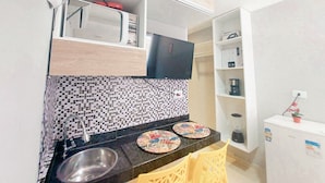 A compact kitchen with a microwave, a sink, and a small countertop. - Residencial Engenheiro Paulo Borba (Ipojuca)