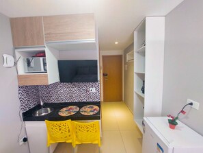 A compact kitchen with a microwave, toaster, and a small dining area with two chairs. - Residencial Engenheiro Paulo Borba (Ipojuca)