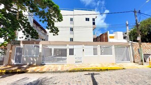 A residential building with a gated entrance, a sign indicating a sale, and a clear blue sky in the background. - Residencial Engenheiro Paulo Borba (Ipojuca)