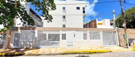 A residential building with a gated entrance, a sign indicating a sale, and a clear blue sky in the background.