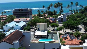 A residential area with a swimming pool, buildings with red-tiled roofs, and a view of the ocean. - Residencial Engenheiro Paulo Borba (Ipojuca)