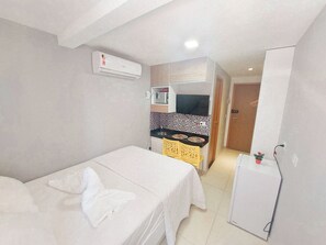 A compact room with a bed, a small kitchenette, and a refrigerator. - Residencial Engenheiro Paulo Borba (Ipojuca)