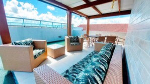A covered outdoor seating area with wicker furniture and a view of the sky. - Residencial Engenheiro Paulo Borba (Ipojuca)