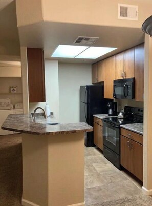 Una cocina con una isla central, un refrigerador, un microondas y armarios de madera.