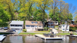 A lakeside property with a dock, a small house, and a larger building with a balcony.