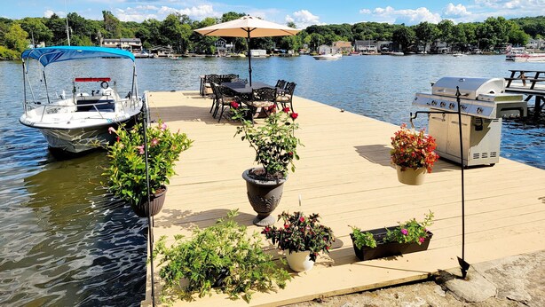 A dock with a boat, outdoor seating, and a grill.