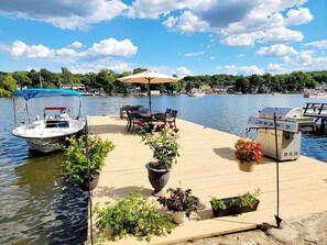 A dock with a boat, outdoor seating, and a grill.