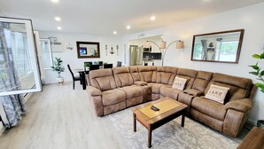 A modern living room with a sectional sofa, a coffee table, and a dining area with a small table and chairs.