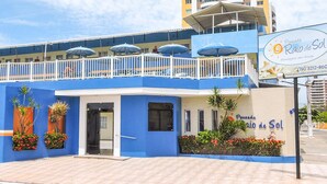A blue building with a balcony, potted plants, and a sign advertising 'Pousada Raio de Sol'. - Pousada Raio de Sol (Aracaju)