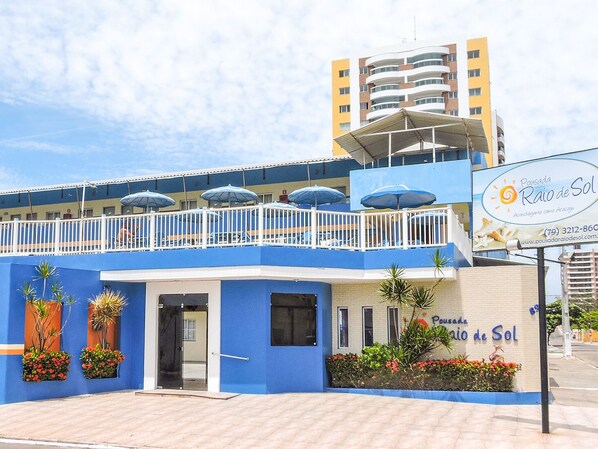 A blue building with a balcony, potted plants, and a sign advertising 'Pousada Raio de Sol'.