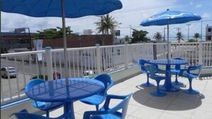 A rooftop terrace with blue tables and chairs, and large blue umbrellas. - Pousada Raio de Sol (Aracaju)
