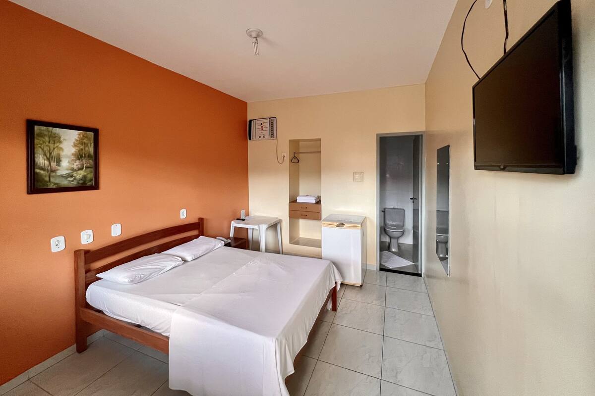 Ein Hotelzimmer mit einem Bett, einem Schreibtisch, einem Sessel, einem Fernseher und einem Badezimmer.