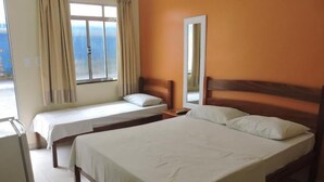 A hotel room with a large bed, a smaller bed, a desk, and a window with curtains. - Pousada Raio de Sol (Aracaju)