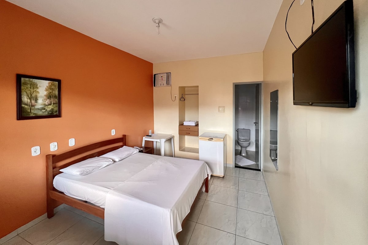 Ein Hotelzimmer mit Bett, Schreibtisch, Fernseher und Badezimmer.