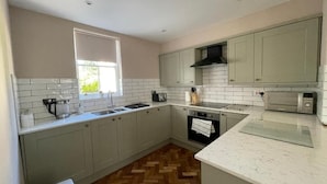 A modern kitchen with light grey cabinets, a herringbone wood floor, a built-in oven, and a microwave.