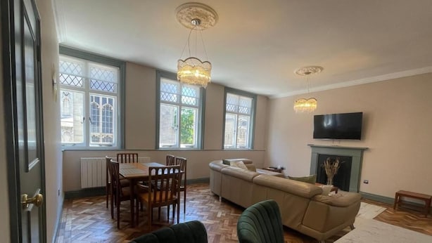 A spacious living room with a dining area, large windows, a fireplace, and a television.