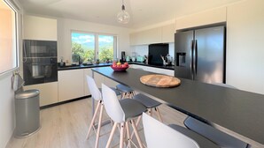 Una cocina moderna con una isla central, electrodomésticos de acero inoxidable y vistas al exterior.