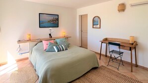 Un dormitorio con cama, mesitas de noche, un escritorio y una silla.