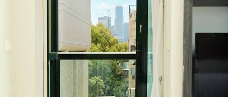 A room with a sliding glass door leading to a balcony, a dark wooden cabinet, and two round ottomans.