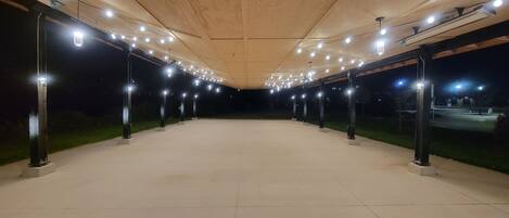 Un pavillon à ciel ouvert doté d’un plafond en bois et d’un éclairage disposé à intervalles réguliers.