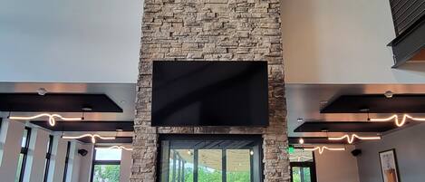 Un interior moderno con chimenea de piedra, ventanas amplias y un televisor de pantalla plana en la parte superior.