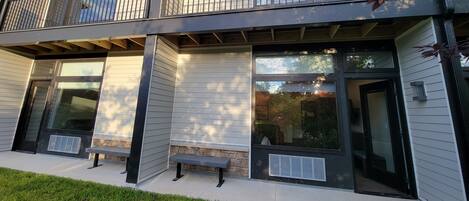 A modern two-story building with a balcony, large windows, and a stone accent wall.
