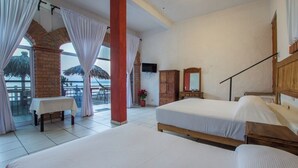 A hotel room with two beds, a TV, a wooden wardrobe, and a balcony with a table and chairs. - Traditional Sierra Leon Oceanfront Rooms (Puerto Vallarta)