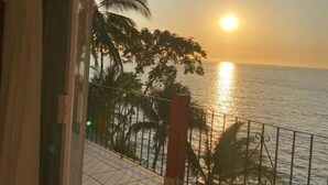 A balcony with a view of the sea and palm trees during sunset. - Traditional Sierra Leon Oceanfront Rooms (Puerto Vallarta)