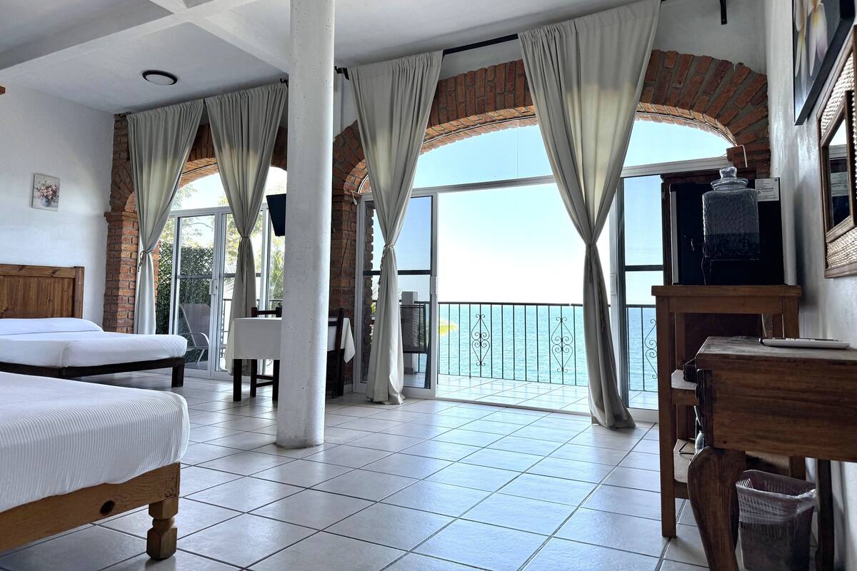 Habitación de hotel con balcón, cama, escritorio y televisor.