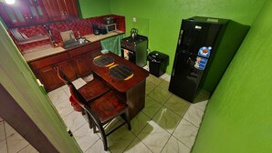 A compact kitchen with wooden cabinets, a microwave, a stove, and a refrigerator. - Xpress Vacations Lifestyle (Ocho Rios)