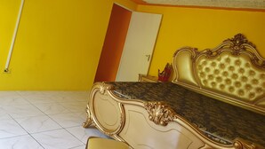 A room with a large bed, a television mounted on the wall, and a door. - Xpress Vacations Lifestyle (Ocho Rios)