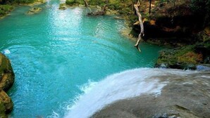 A natural water body surrounded by rocks and vegetation. - Xpress Vacations Lifestyle (Ocho Rios)