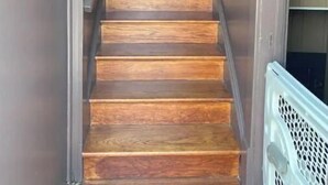 A wooden staircase leading to a door with a frosted glass panel. - Fairy Bowery (Nauvoo)