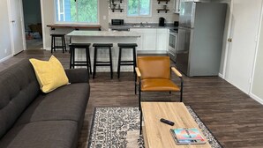 Une cuisine moderne avec des meubles blancs, un réfrigérateur en acier inoxydable et un coin bar équipé de tabourets.