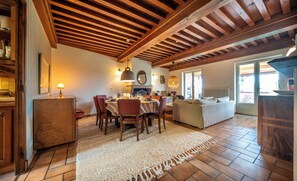A dining area with wooden beams, a fireplace, and a dining table set for four.