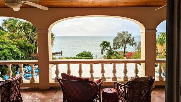 Een balkon met rieten stoelen en uitzicht op zee.