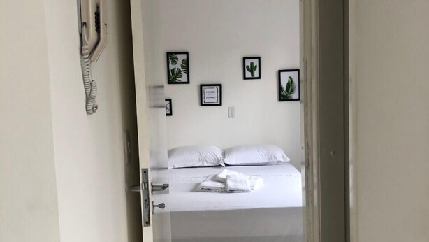 Una habitación con cama, una puerta y una pared decorada con marcos.