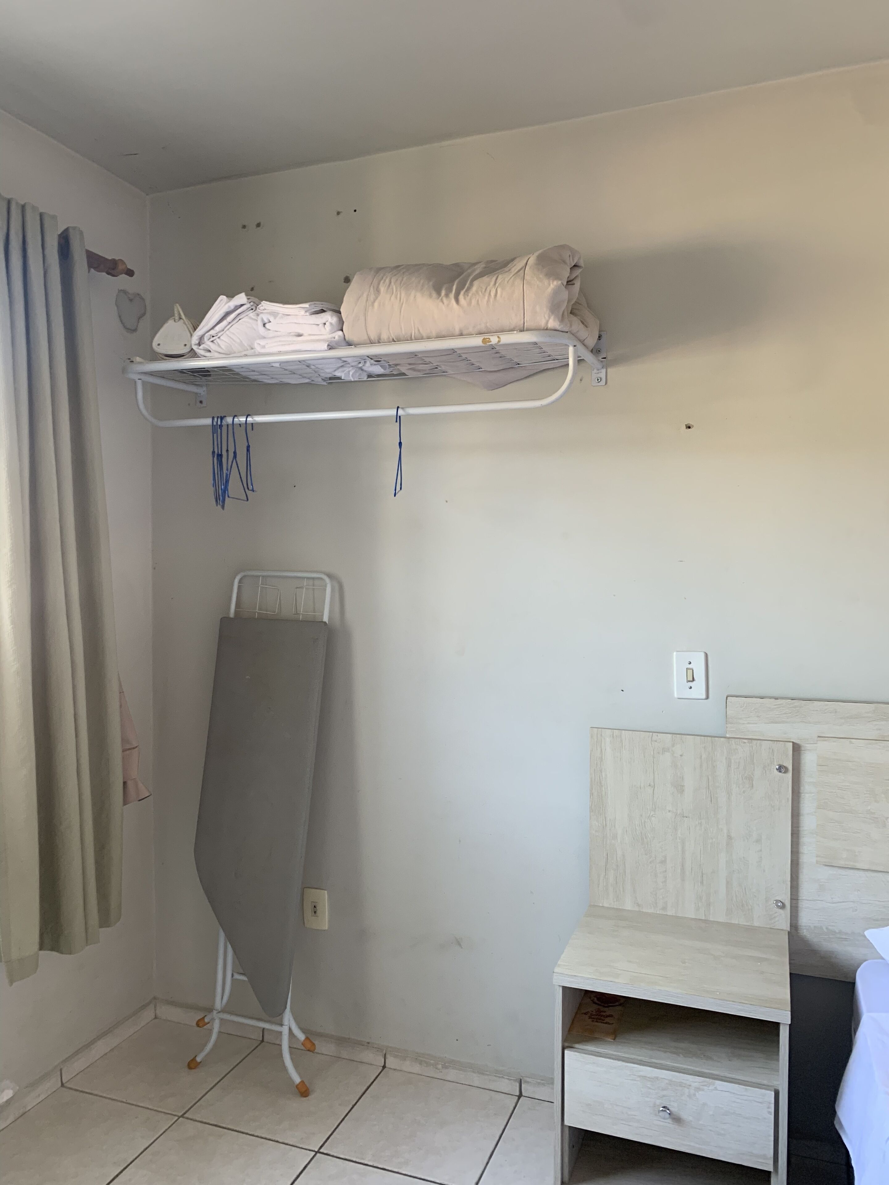 A bedroom with a bunk bed, a standing heater, a bedside table, and a wooden nightstand.