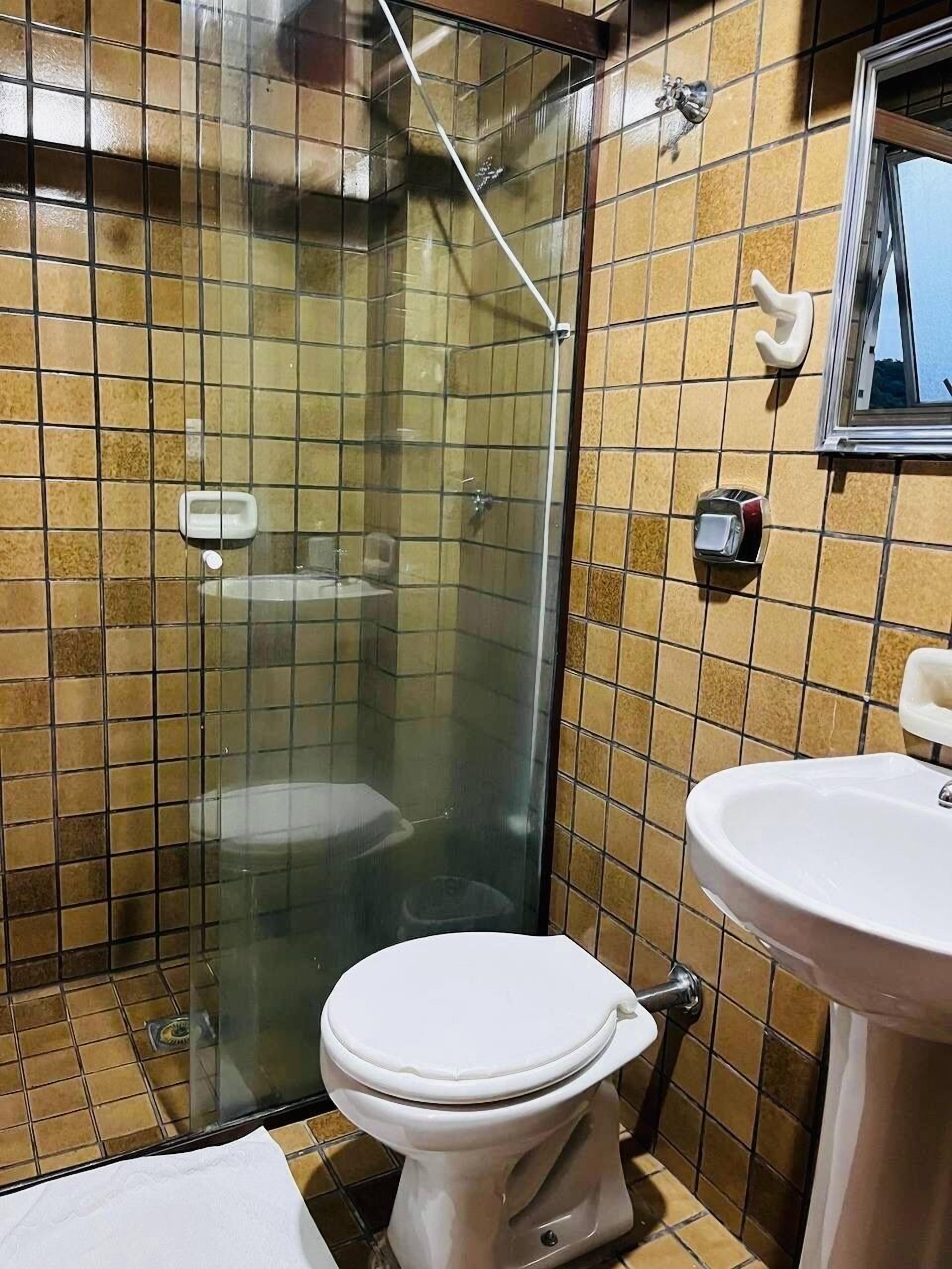 A bathroom with a glass-enclosed shower, a toilet, and a sink.