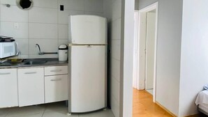 Una cocina compacta con armarios blancos, un lavabo, un microondas y un refrigerador.