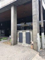 Entrada do Edifício Abdon, com uma grande fachada de vidro e duas portas cinzas identificadas como 