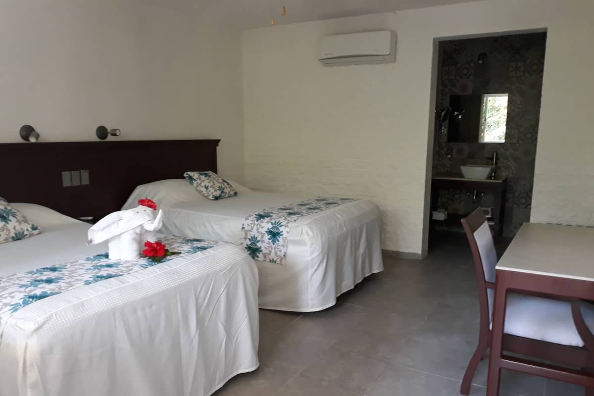 Ein Hotelzimmer mit zwei Betten, einem Holzkopfteil, einem kleinen Tisch und einem Stuhl.